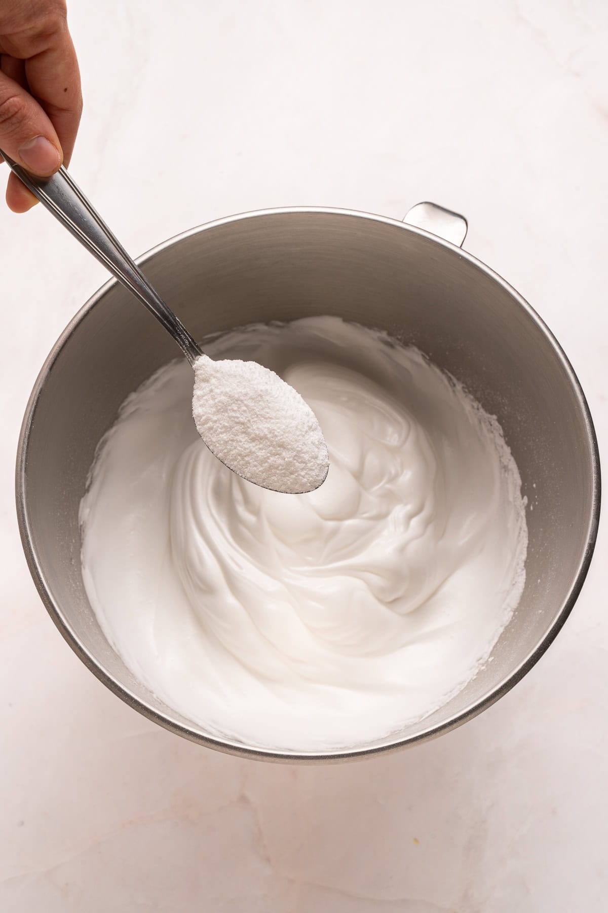 Adding sugar to the whipped egg whites.