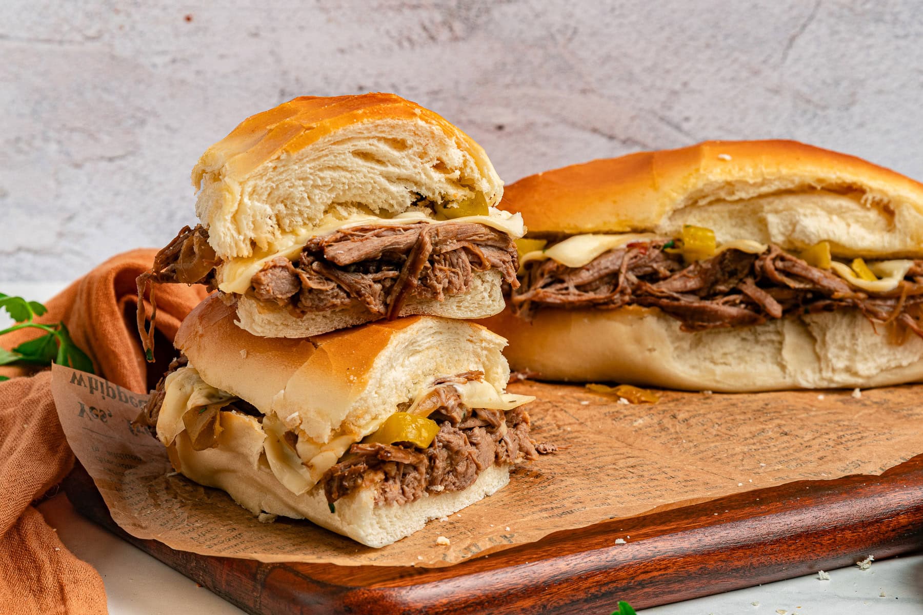 Sandwiches stacked on paper and a full sandwich. 