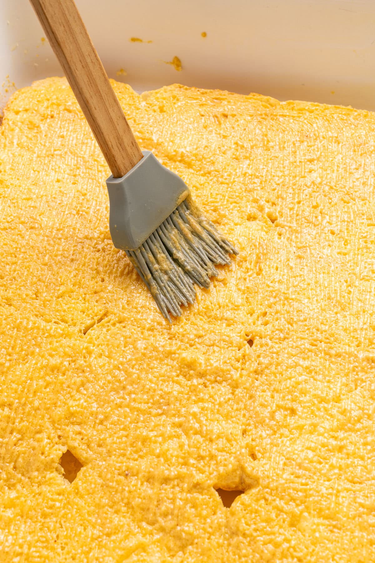 Brushing melted butter and Dijon on rolls.