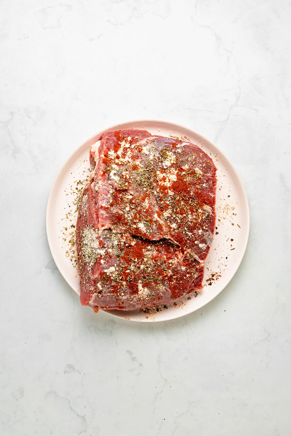 Raw chuck roast with seasonings.
