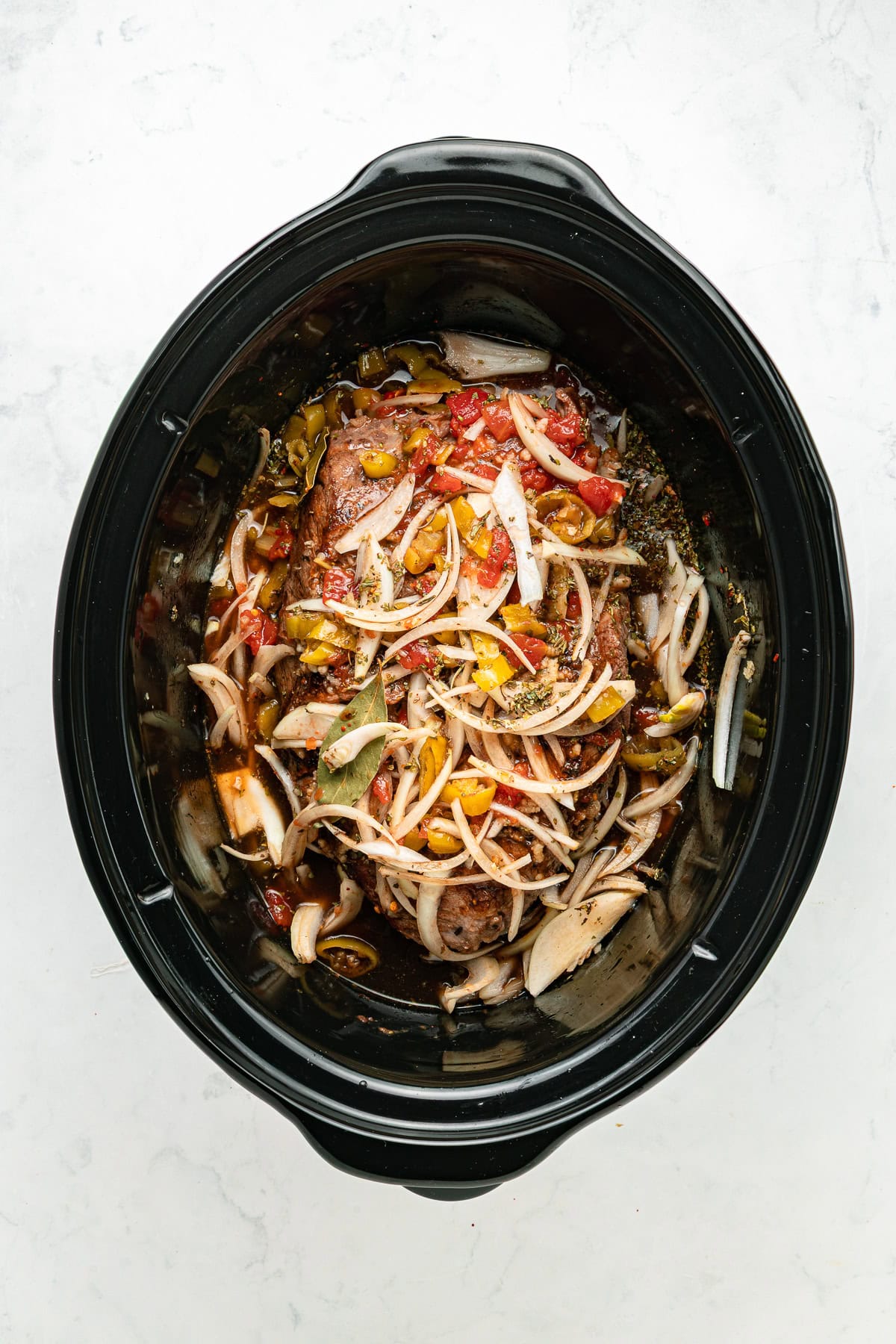Italian beef ingredients combined in a slow cooker.