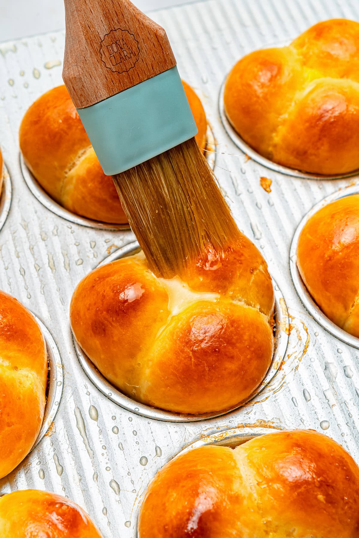 Brushing butter on freshly baked rolls.